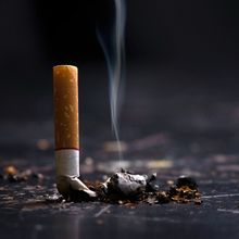 stubbed-out cigarette with smoke rising from ashes